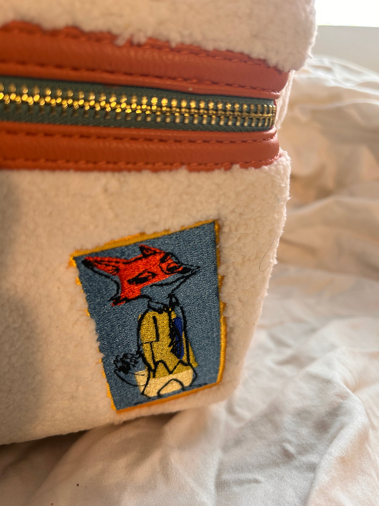 Whimsical Details: Adorned with iconic patches including Judy Hopps, a carrot, and the ZPD badge.Premium Quality: Crafted with high-quality craftsmanship, featuring a cloisonné Disney Parks x Loungefly metal plate and orange vegan leather trim.Functional Design: Includes a front zip pocket, two side slip pockets featuring sloths Flash and Priscilla, and adjustable padded shoulder straps.Compact & Durable: Measuring approximately 10.5" H x 9.5" W, it is made of durable polyurethane with a 100% polyester lini