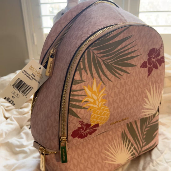 Vibrant, playful print of golden pineapples, lush palm fronds, and hibiscus blooms set against the iconic MK signature logo canvas.
 The "Medium" size is the ultimate sweet spot—compact enough for a sleek profile but spacious enough to hold your tablet, wallet, and essentials with ease.
Premium Details: Outfitted with gleaming gold-tone hardware and high-quality zip fastenings that offer both luxury and durability. Designed with multiple zippered compartments.