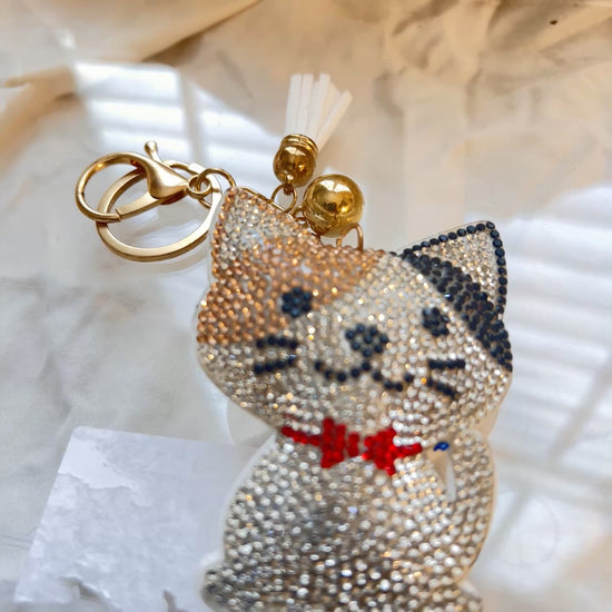 Cat keychain featuring a charming hand plushed texture&nbsp;

It wears a signature red bowtie and a premium gold clasp closure.&nbsp;

Whimsical accessory to elevate any handbag, backpack, or of course set of keys.